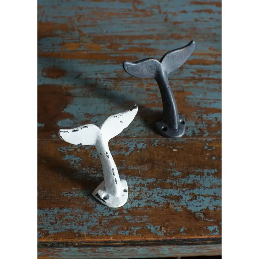 White and black cast iron whale tail wall hooks on weathered blue wood