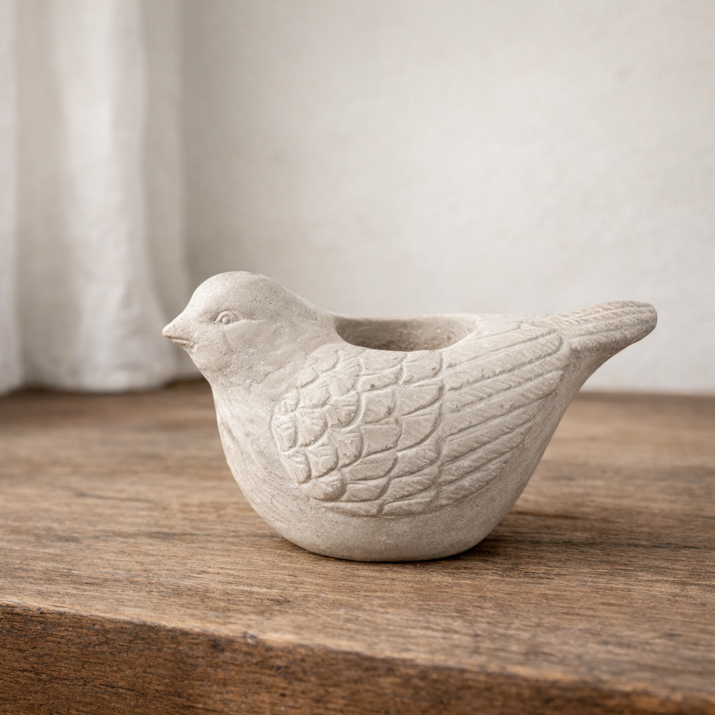 Large cement bird candle holder isolated against a neutral background
