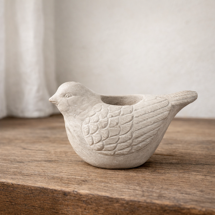 Large cement bird candle holder isolated against a neutral background