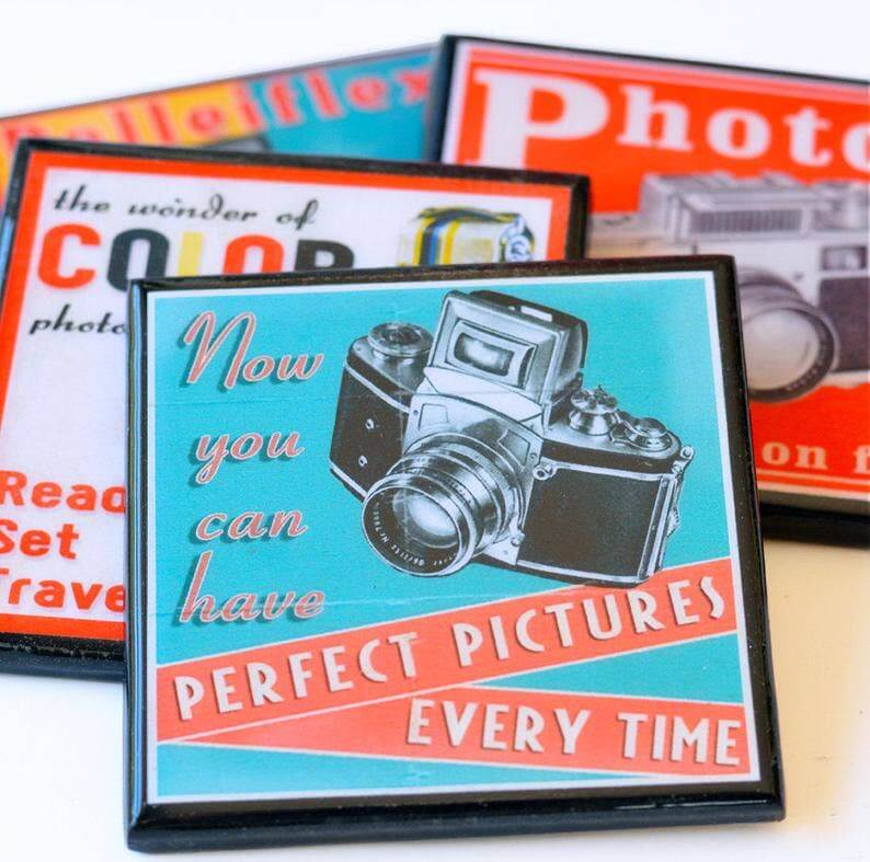 Decorative photo coasters with camera illustration and text on a white surface