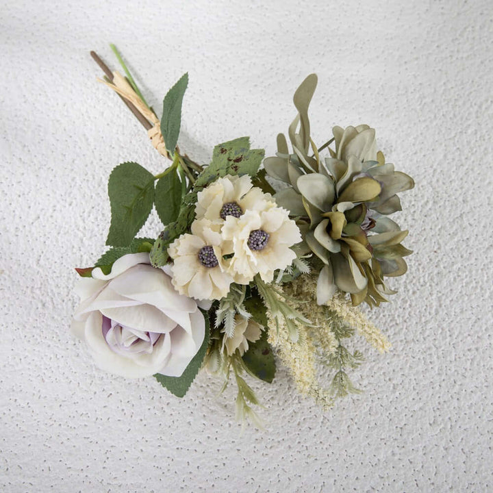 Faux flower bouquet featuring a rose, garden blooms, and greenery on a textured background.