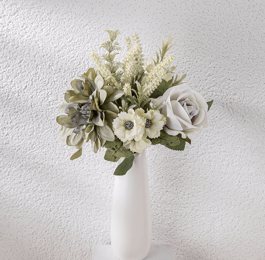 Faux flower bouquet featuring roses and garden blooms in a elegant white vase against a textured background.