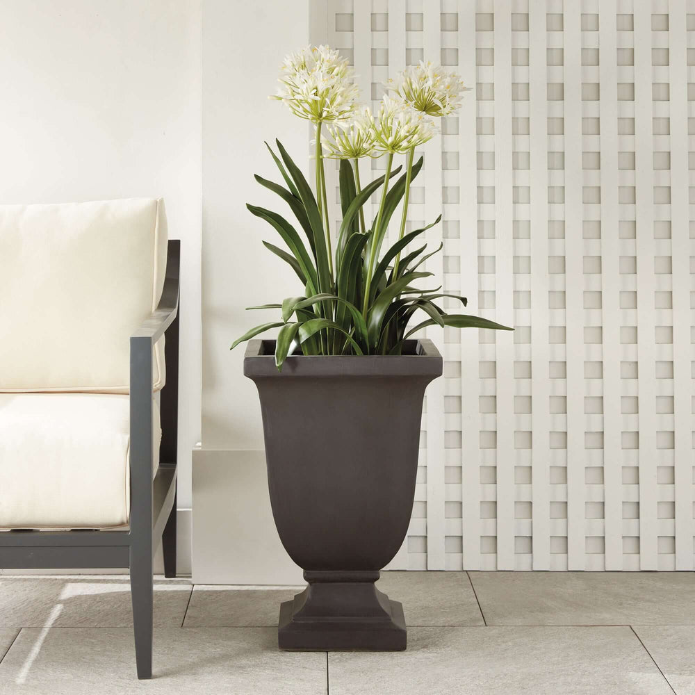 Fibreclay footed planter with flowers in vintage garden decor, showcasing elegant silhouette and charcoal finish.