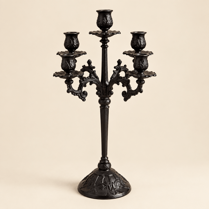 Ornate black cast iron candelabra with five candle holders against an ivory studio background