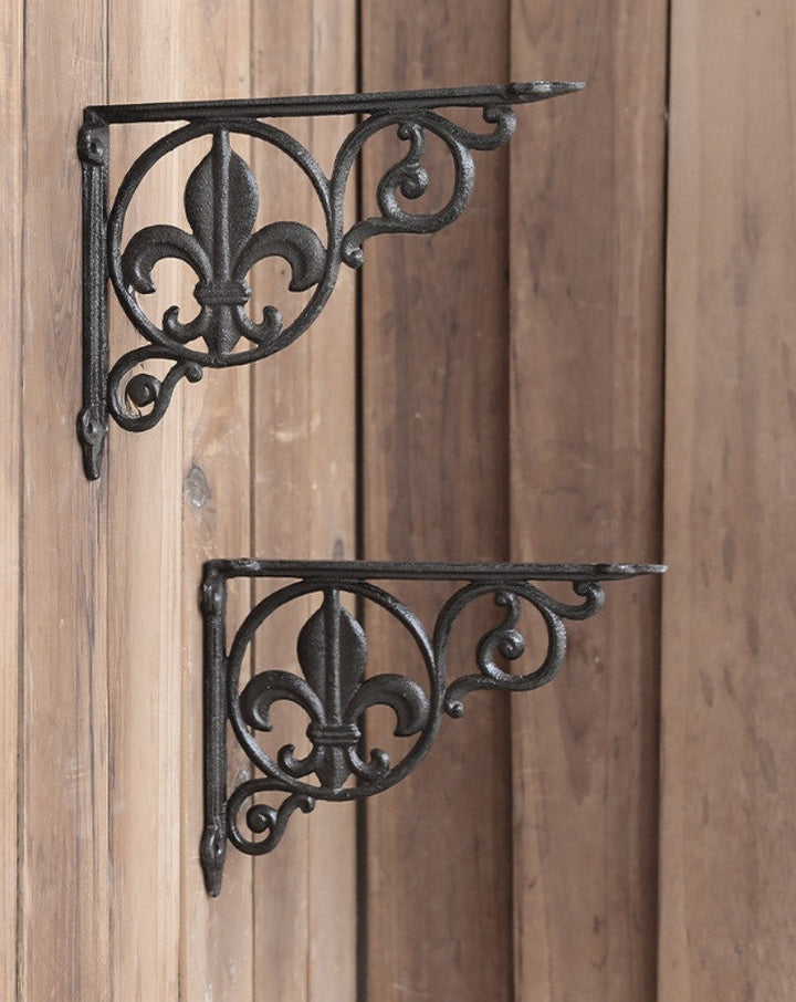 Pair of Fleur-de-Lis Cast Iron Shelf Brackets against wood paneling