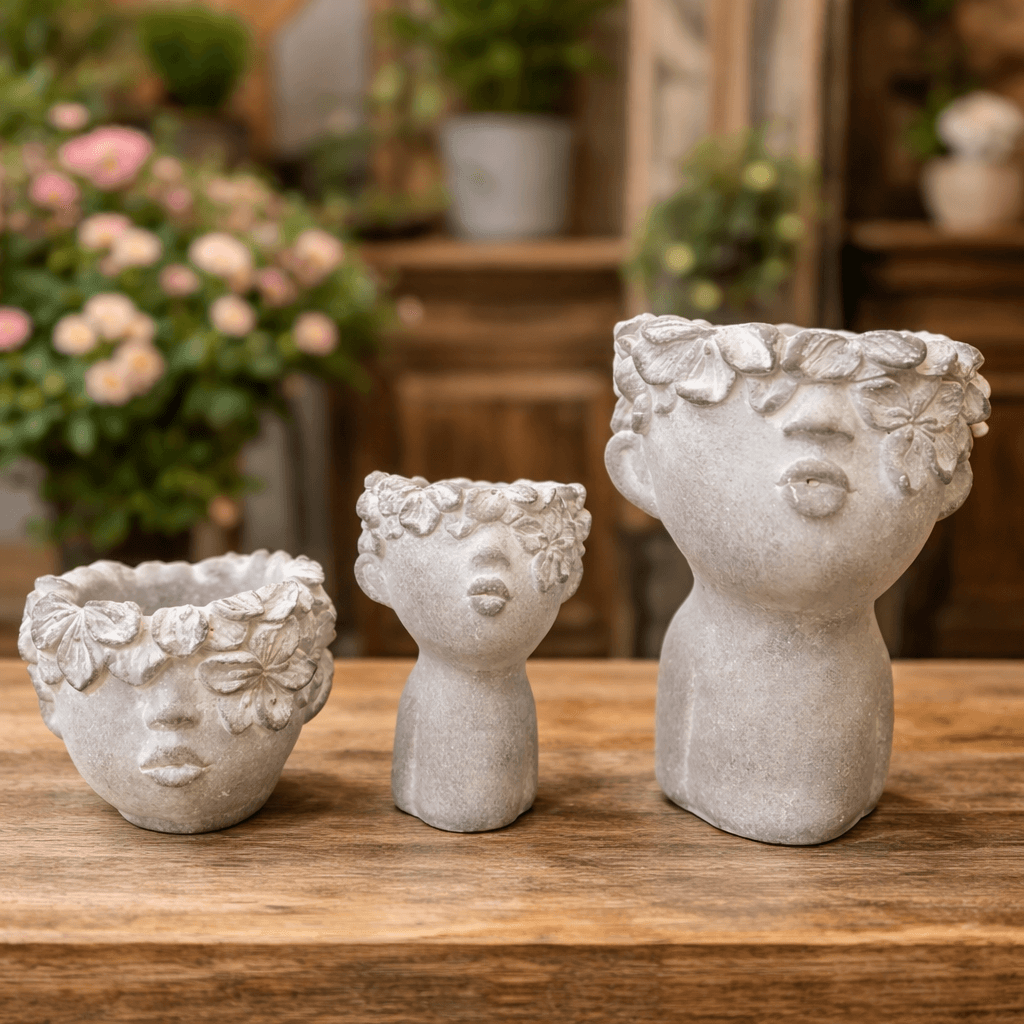 Three flower-crowned concrete face planter forms on a wooden table