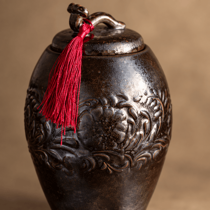 Close-up of the dark brown glaze and raised floral decoration on a ceramic storage jar.