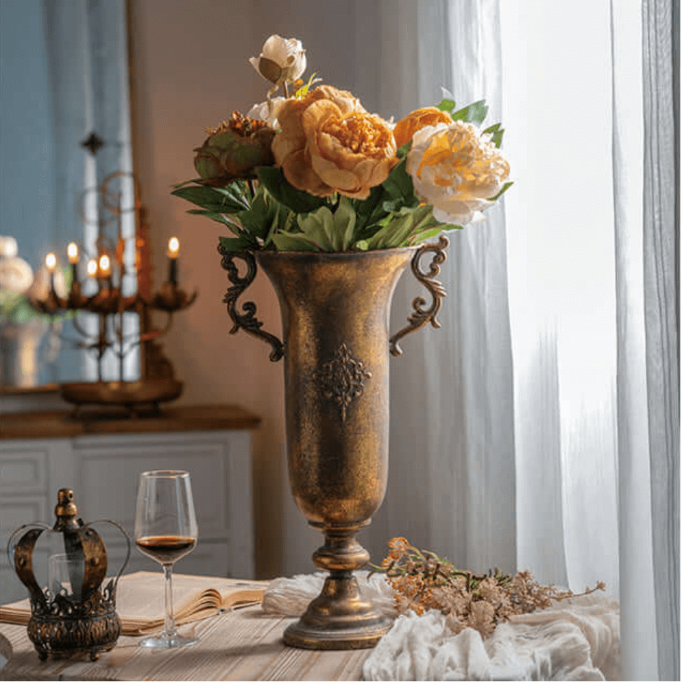 Decorative vase with flowers on a table in a room with a chandelier and candles.
