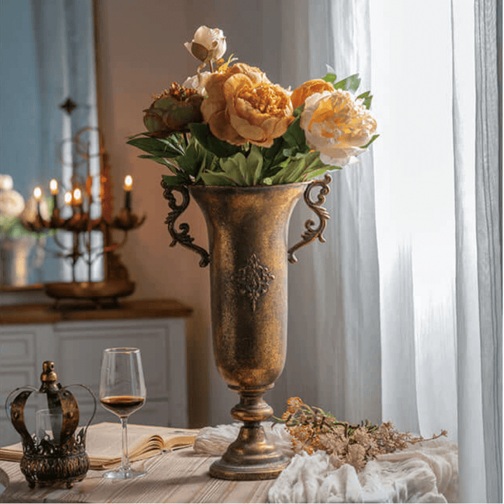 Decorative vase with flowers on a table in a room with a chandelier and candles.