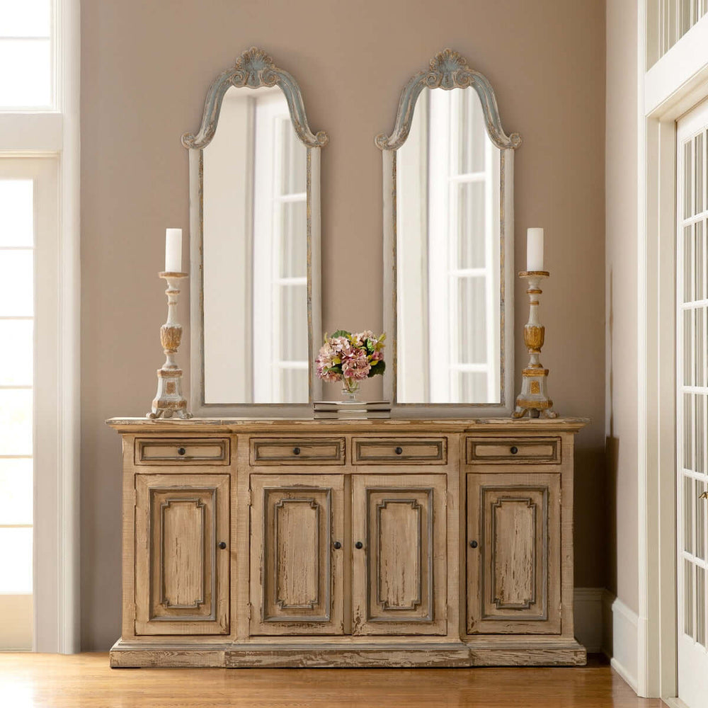 Elegant French country decor with carved wood mirrors and distressed sideboard