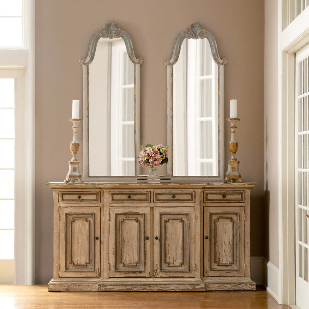 Elegant French country decor with carved wood mirrors and distressed sideboard