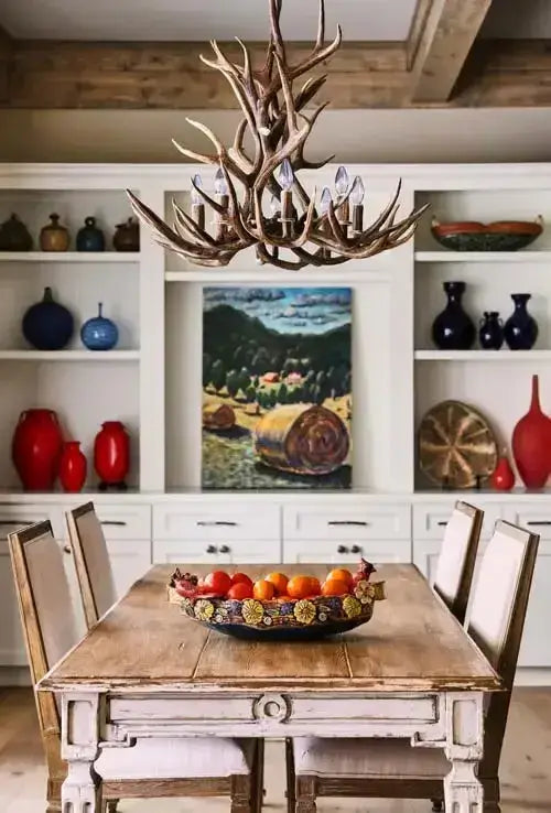 French Country Sage Dining Table with Natural Wood Top in rustic kitchen setting with antler chandelier and decorative shelves.