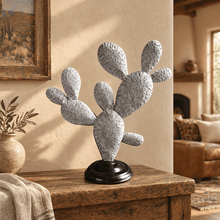 Galvanized prickly pear cactus sculpture styled on a rustic wood console in a warm neutral interior.