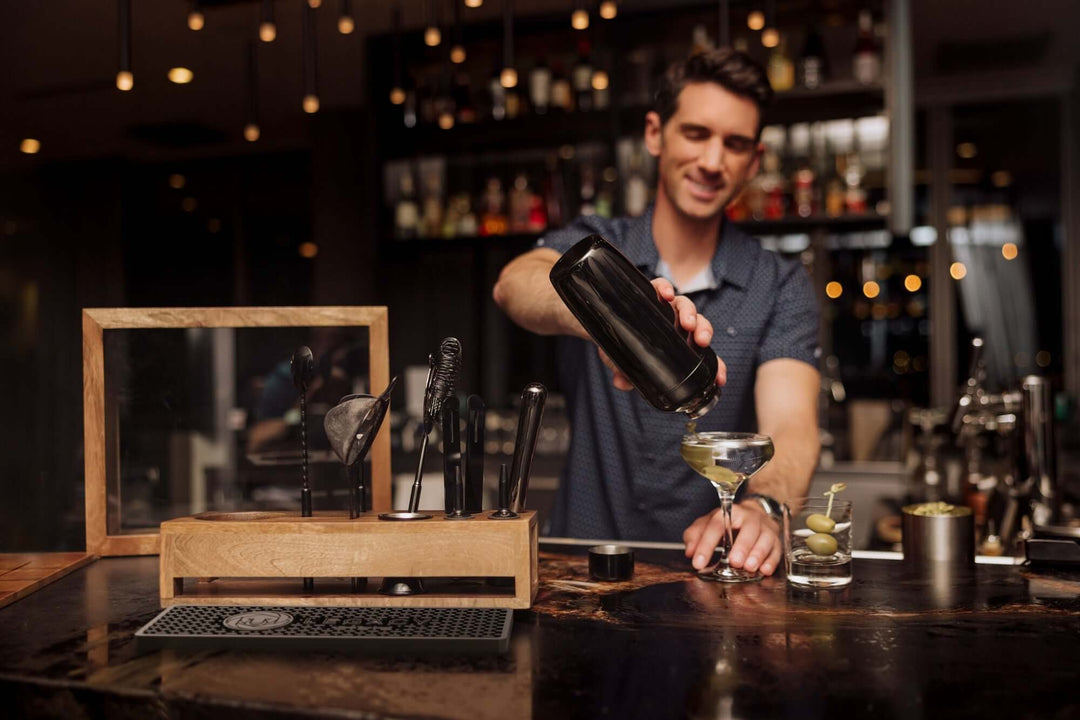 Bartender using Vintage-Style Bartender Kit with Mango Wood Case & Bar Tools in a dimly lit bar setting