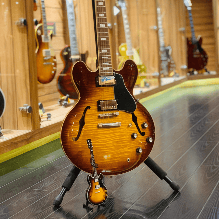 Gibson ES-335 Vintage Sunburst Mini Guitar Replica displayed on stand in guitar showcase