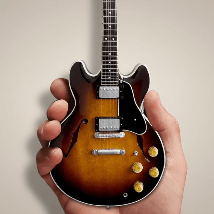 Hand holding Gibson ES-335 Vintage Sunburst Mini Guitar Replica, a detailed 1:4 scale collectible of the classic 1958 electric guitar.