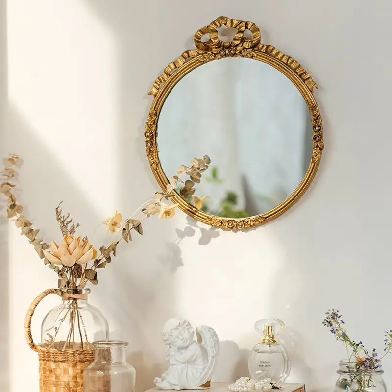 Oval wall mirror with ribbon crest mounted above a collected console