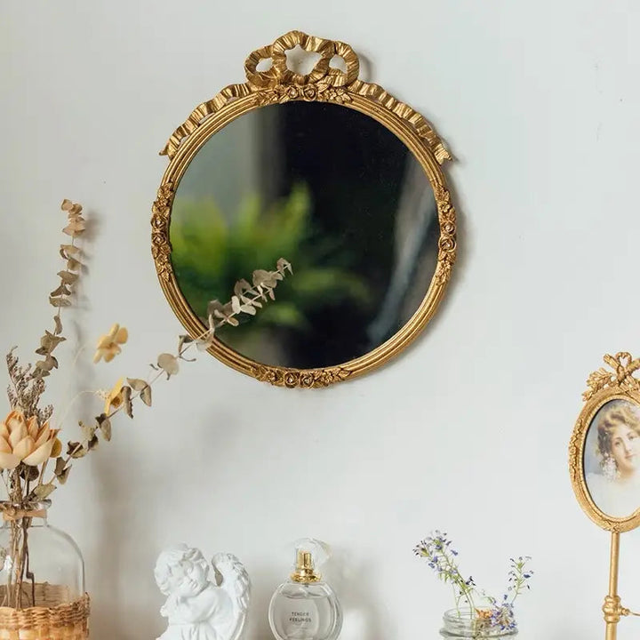 Gilded oval mirror reflecting greenery in a sunlit room