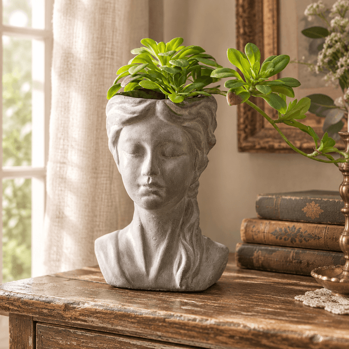 Braided girl cement planter with green foliage styled on a wooden console in a cottage interior.