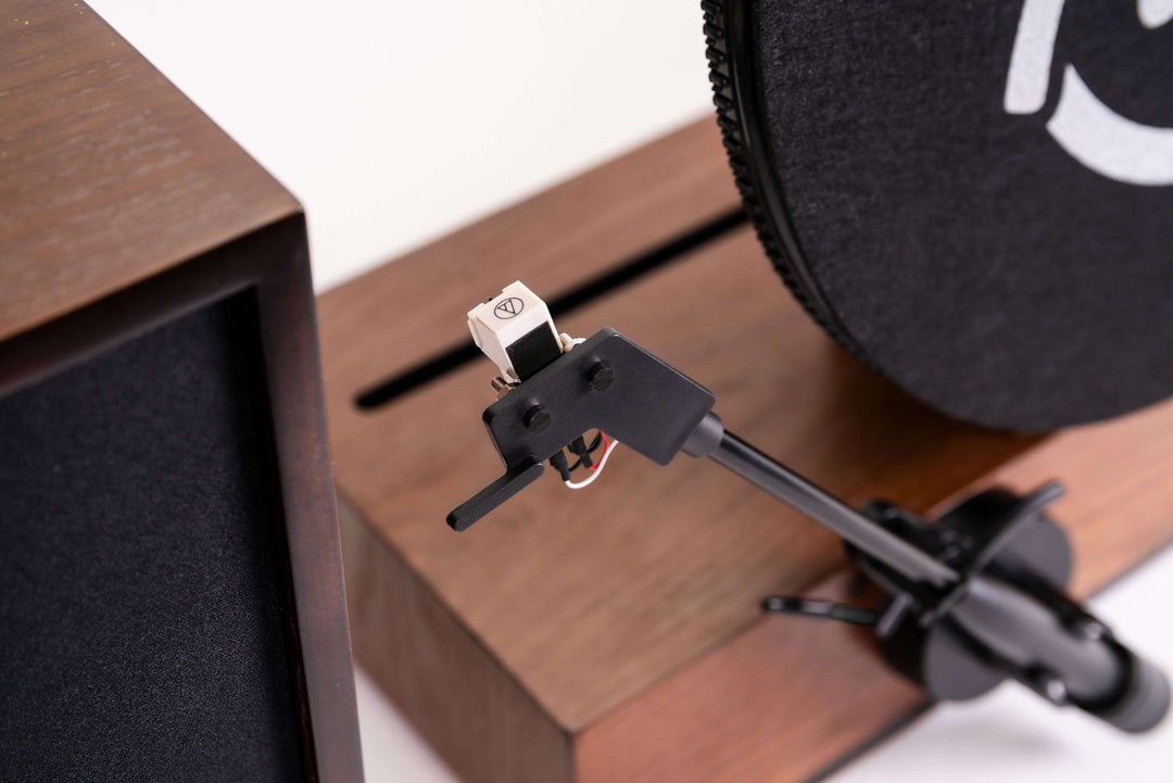Close-up of a turntable needle on a wooden turntable with a white background