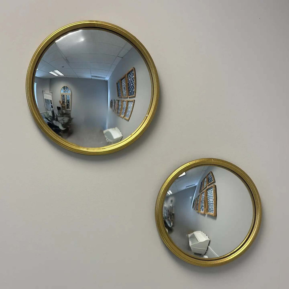Small and medium gold-framed round convex wall mirrors displayed together