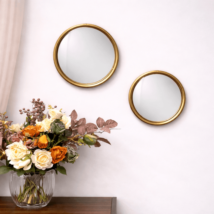 Pair of gold round convex wall mirrors above a floral console arrangement