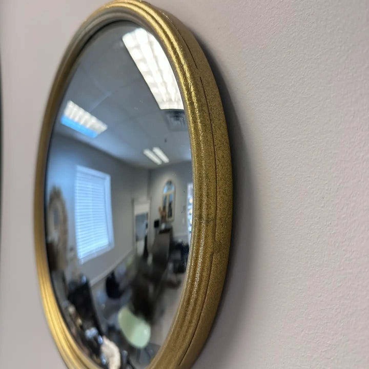 Side profile of a slim gold metal frame around convex mirror glass