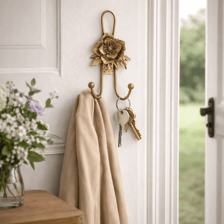 Gold iron flower wall hook holding a linen wrap and keys in a bright cottage entry