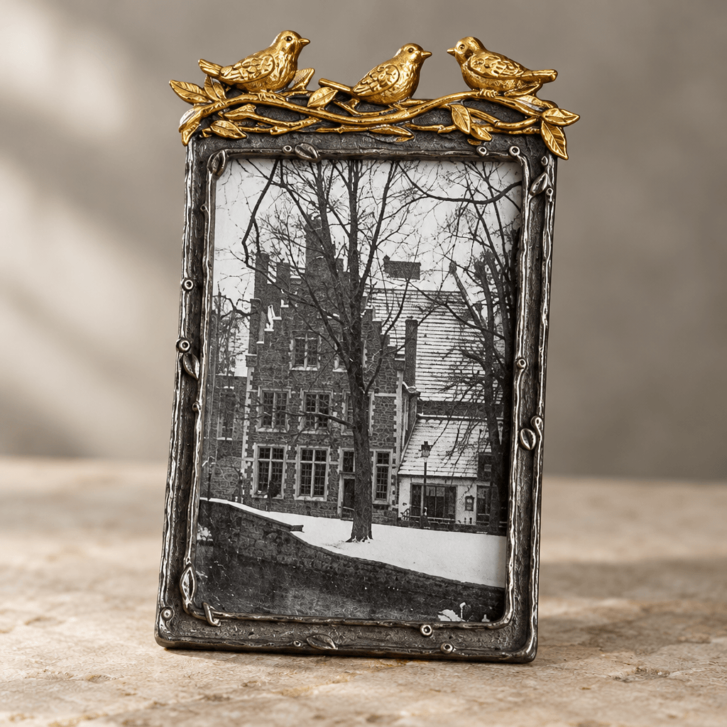 Close detail of gold-leaf bird accents and the textured branch-like pewter border of a vertical photo frame.