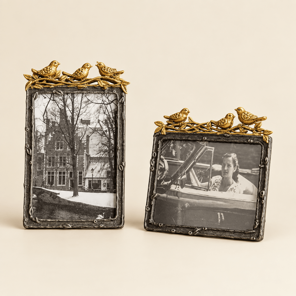 Vertical and horizontal pewter photo frames with gold-leaf bird accents on an ivory studio background.