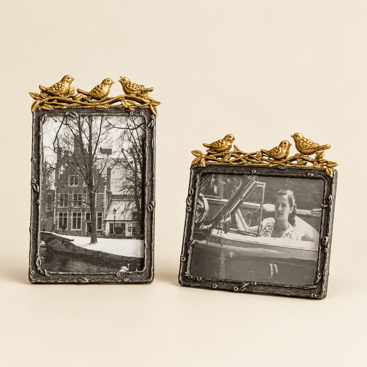 Vertical and horizontal pewter photo frames with gold-leaf bird accents on an ivory studio background.