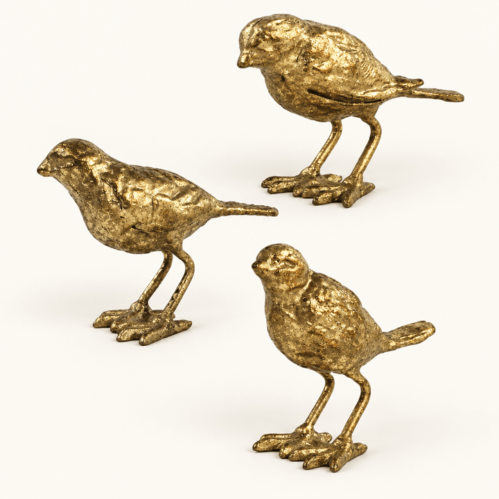 Three textured gold-leaf cast iron bird figurines arranged on an ivory background.
