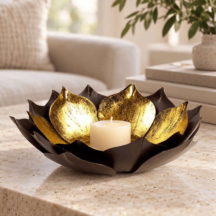 Gold-leaf lotus candle bowl with an ivory votive on a pale stone living room table
