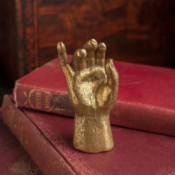 Gold Leaf Pewter Blessing Hand Figurine displayed on red antique books