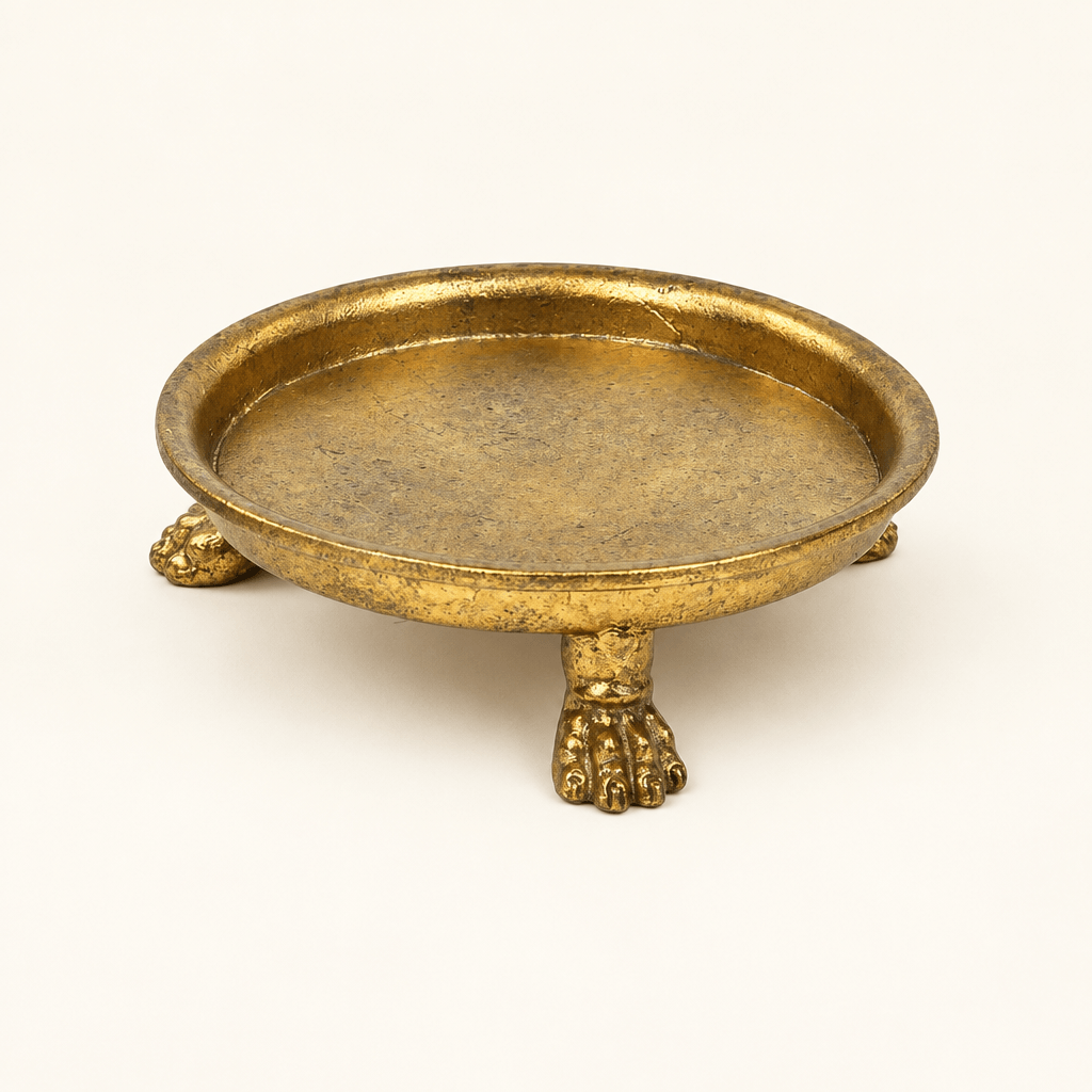 Round gold-leaf pewter dish with sculptural claw feet on an ivory studio background.