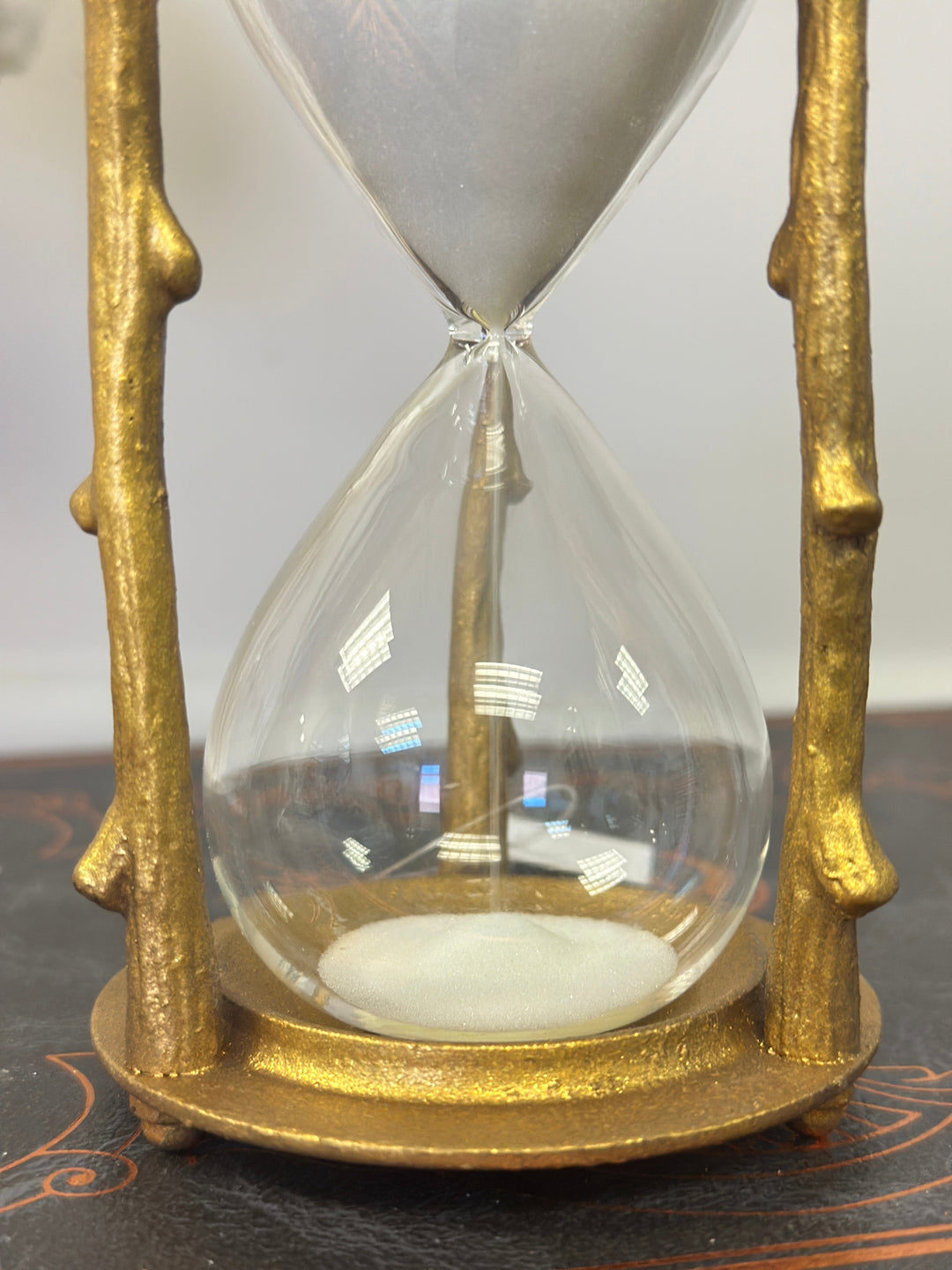 Close view of white sand falling through the clear glass hourglass