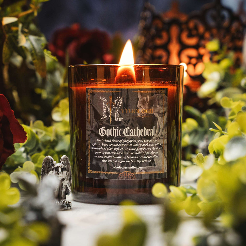 Gothic Cathedral Candle with patchouli scent, burning amidst greenery and shadows, evoking medieval sanctuary mystery.