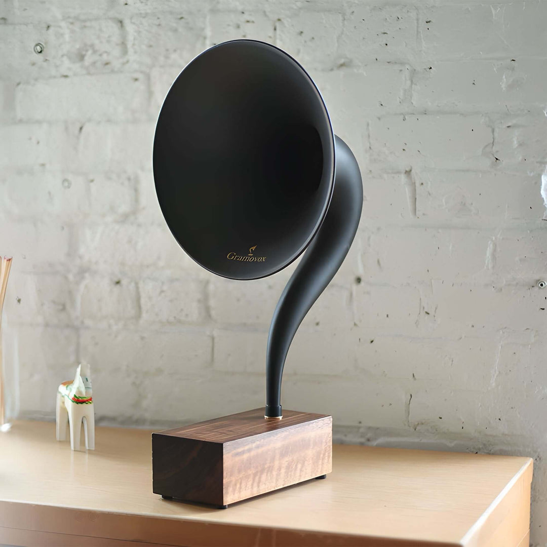 Gramovox Bluetooth Gramophone Speaker on a wooden table against a white brick wall, showcasing vintage design with modern sound.