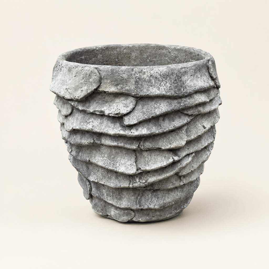 Grey cement palm leaf planter with overlapping leaf relief on an ivory studio background