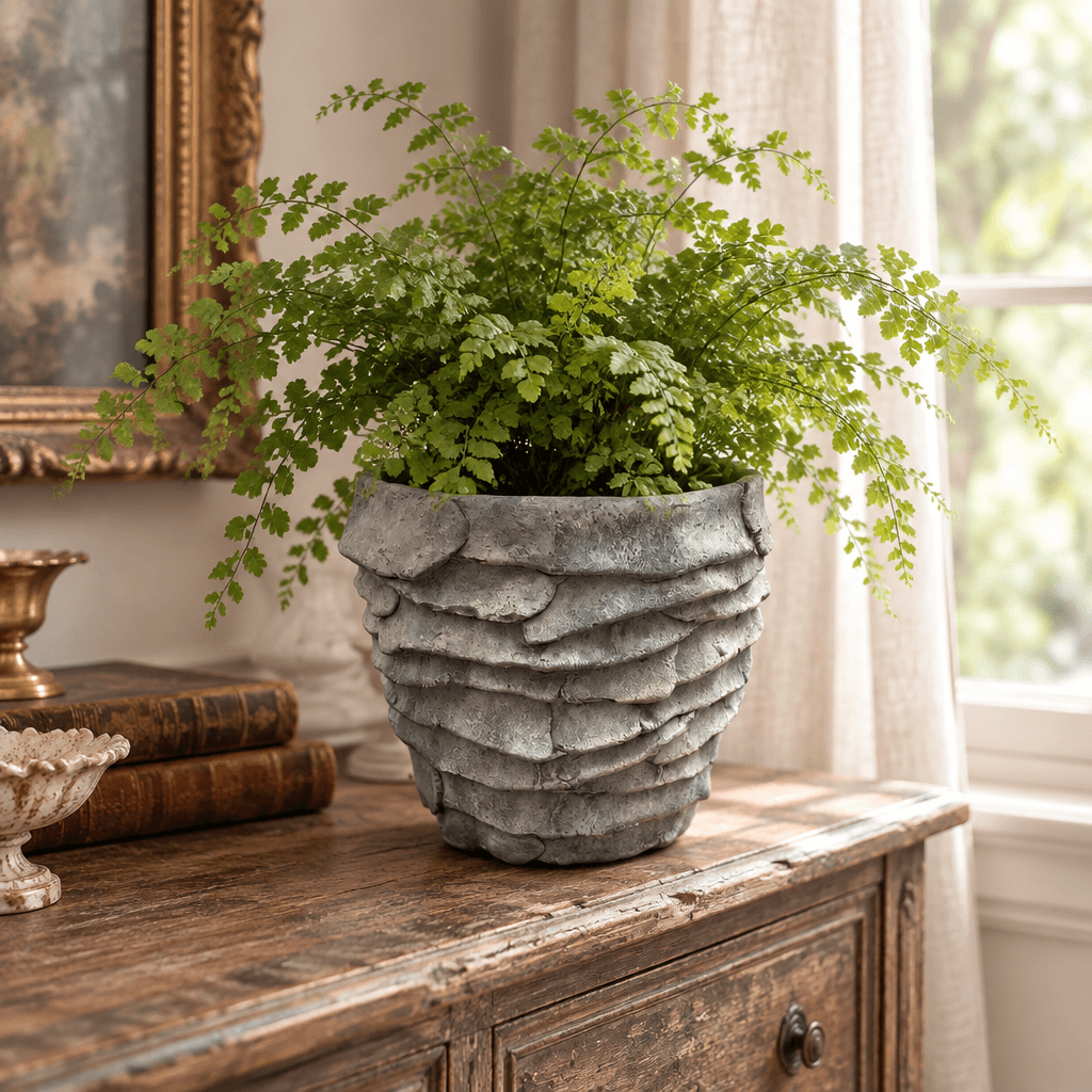 Grey cement palm leaf planter styled with a fern on a wooden console in a vintage-inspired interior
