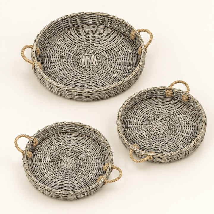 Three grey-washed round willow trays with jute handles on an ivory background