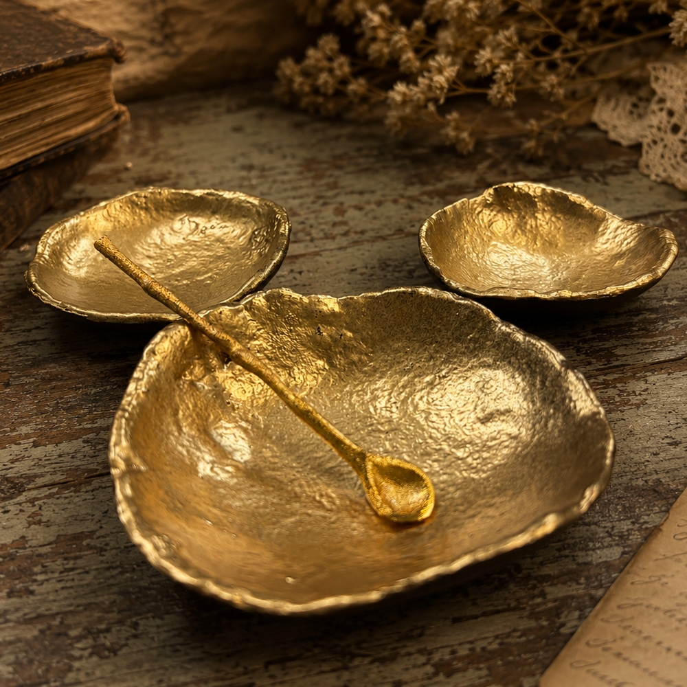 Gold condiment dish set and spoon arranged on a wood surface