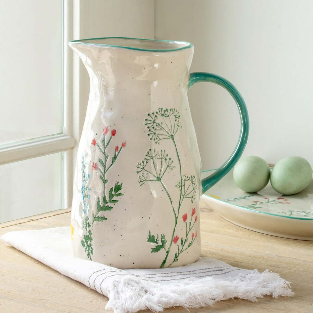 Hand-Painted Ceramic Wildflower Pitcher with delicate flower motifs in a cottagecore style on a wooden table.