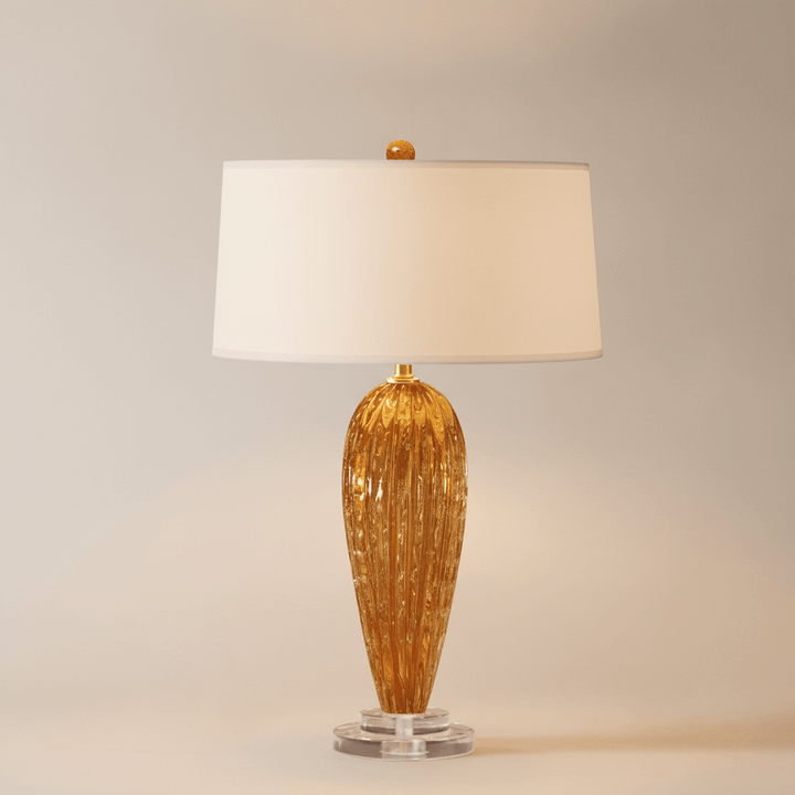Table lamp with gold base and white shade on a neutral background