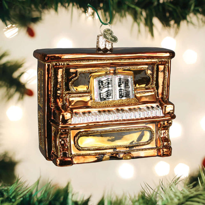 Glass Upright Piano Christmas Ornament hanging on a Christmas tree branch, showcasing handcrafted design and intricate details.