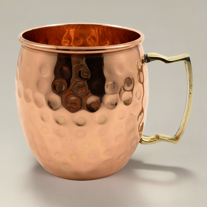 Copper mug with a gold handle on a gray background