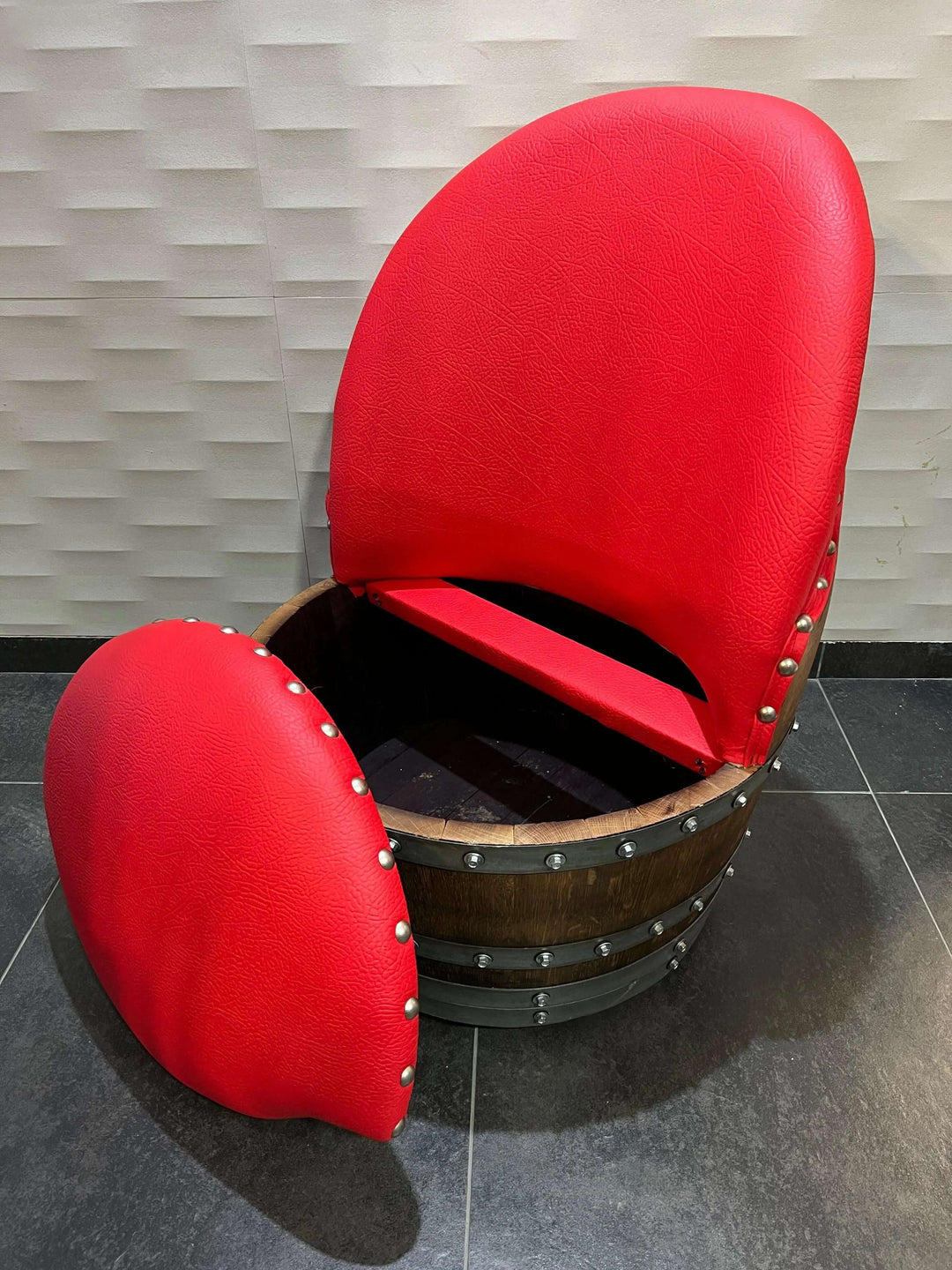 Handcrafted red cushioned chair made from vintage oak barrel, showcasing unique design and rustic elegance.