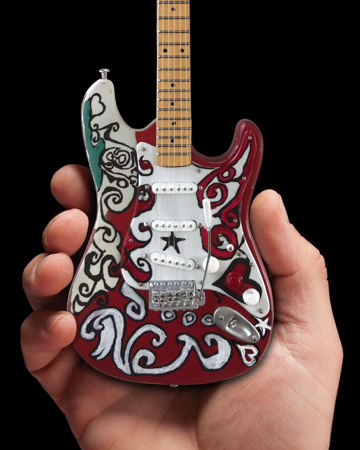 Hand holding Jimi Hendrix Fender Stratocaster Mini Guitar Replica showcasing intricate design.