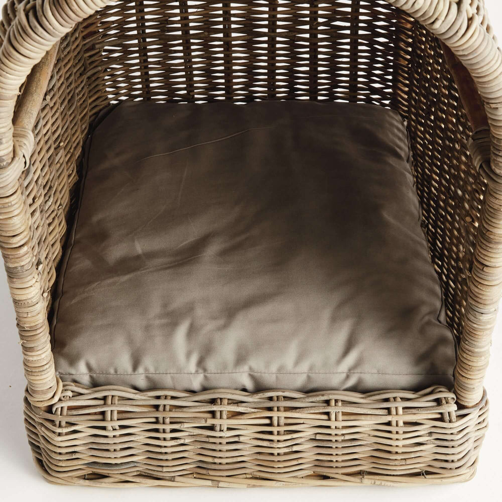 Handwoven rattan dog bed with plush cushion, offering cozy retreat for pets.