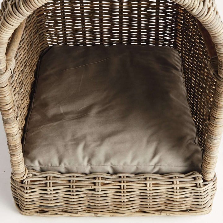 Handwoven rattan dog bed with plush cushion, offering cozy retreat for pets.